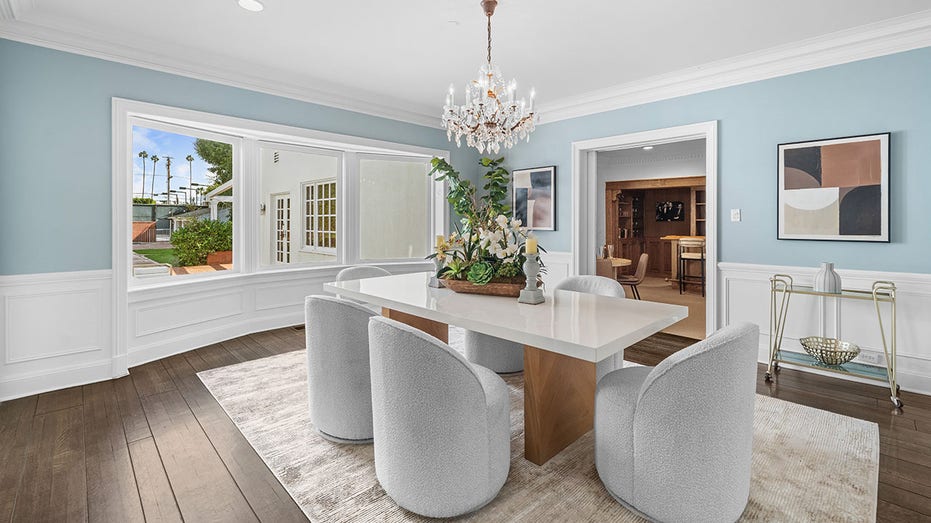 Connected to the kitchen is the formal dining room, which features blue walls with artwork hanging off them.