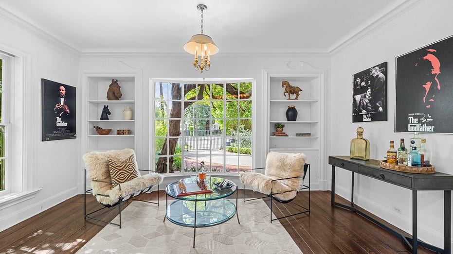 A less formal sitting area features built-in bookshelves, a window looking out onto the front yard and movie posters.