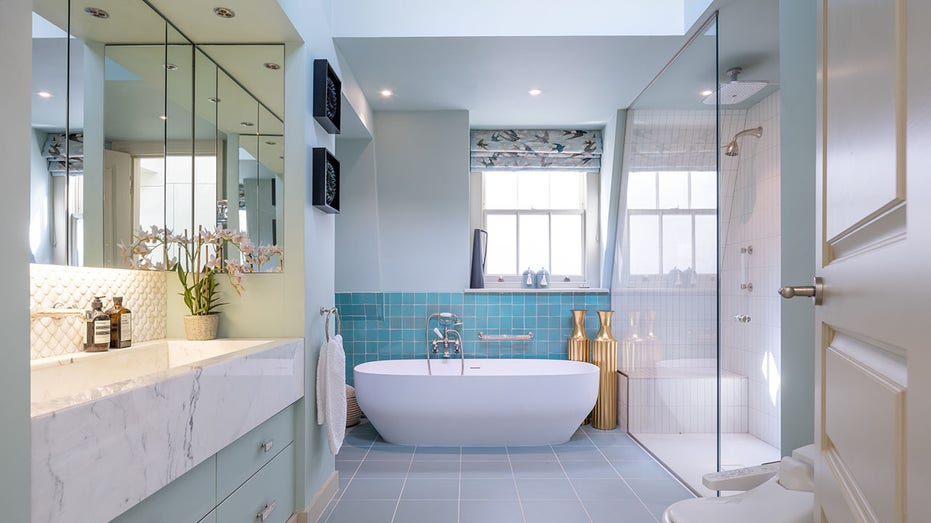 The luxurious ensuite bathroom features blue tile, a standing shower and a soaking tub.