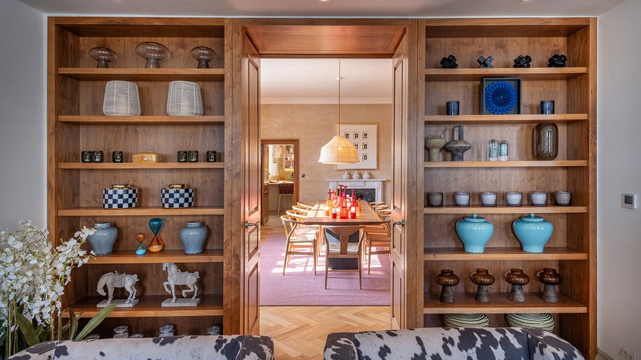 Custom floor-to-ceiling built-in shelves separate the reception room from the dining room.