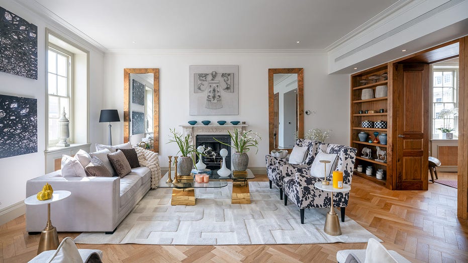 The reception room features a white marble fireplace with two mirrors placed on either side.