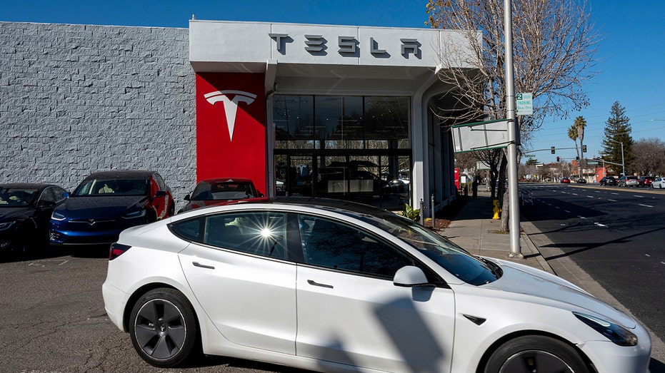 Tesla Model 3 mengemudi di luar toko Tesla