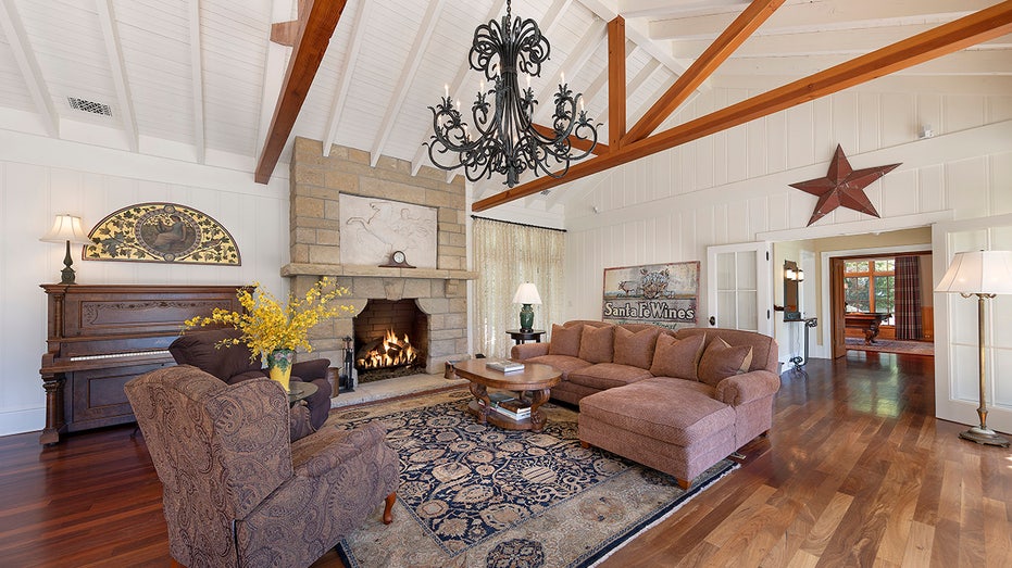 The great room boasts exposed wooden beams on the ceiling and a wood-burning fireplace.