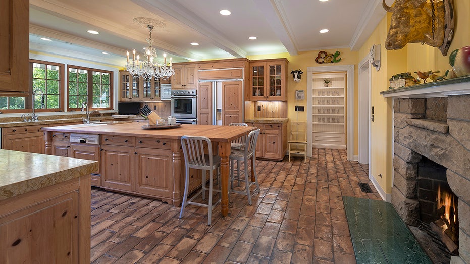 The kitchen features a large center eat-in island with a chandelier over it.