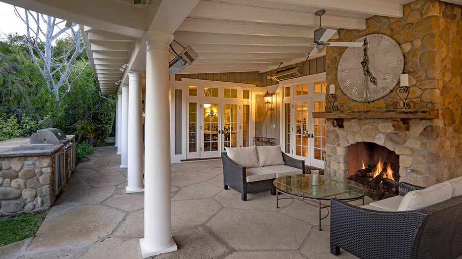 The backyard features an outdoor living room with a fireplace and an outdoor kitchen.