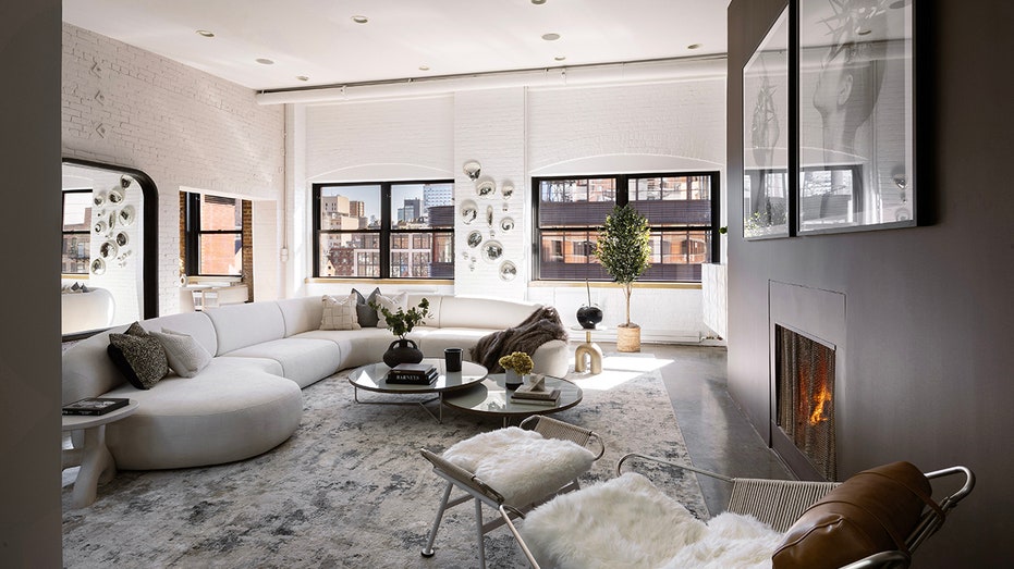 The living room features white brick walls, a wood-burning fireplace and big windows.