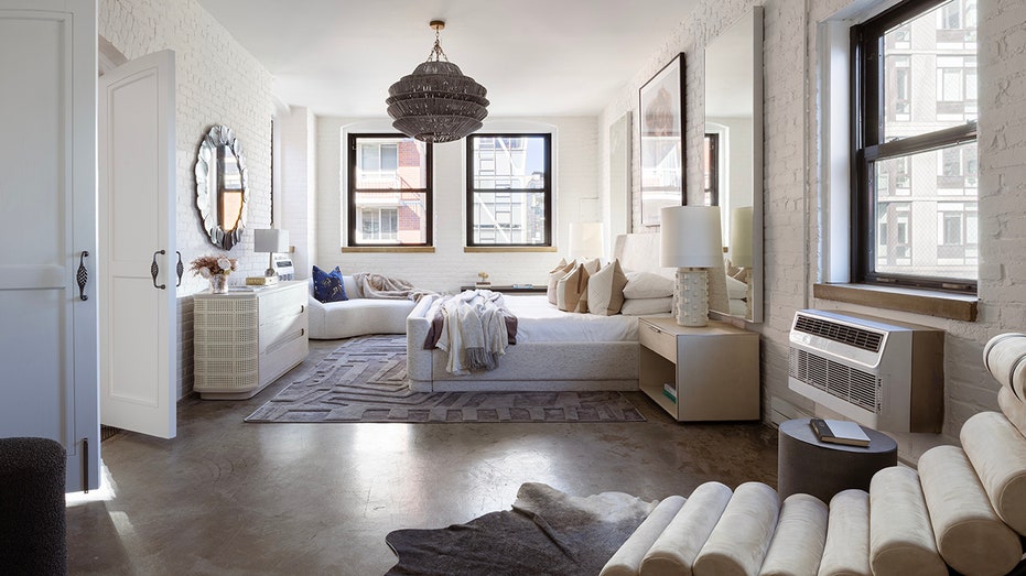 The spacious primary bedroom is accessed through white double doors and features neutral-colored furniture.