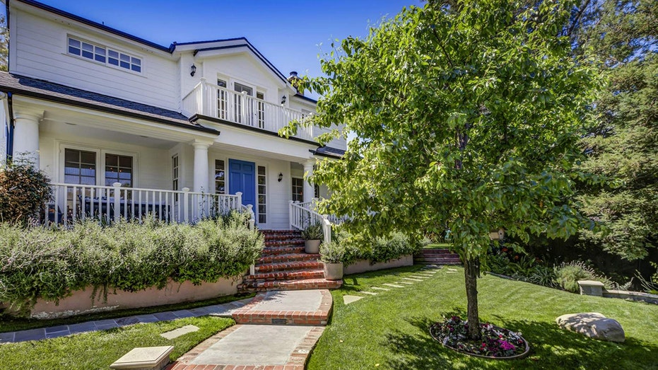 A stone walkway with lush green grass on either side leads to the home's front door.