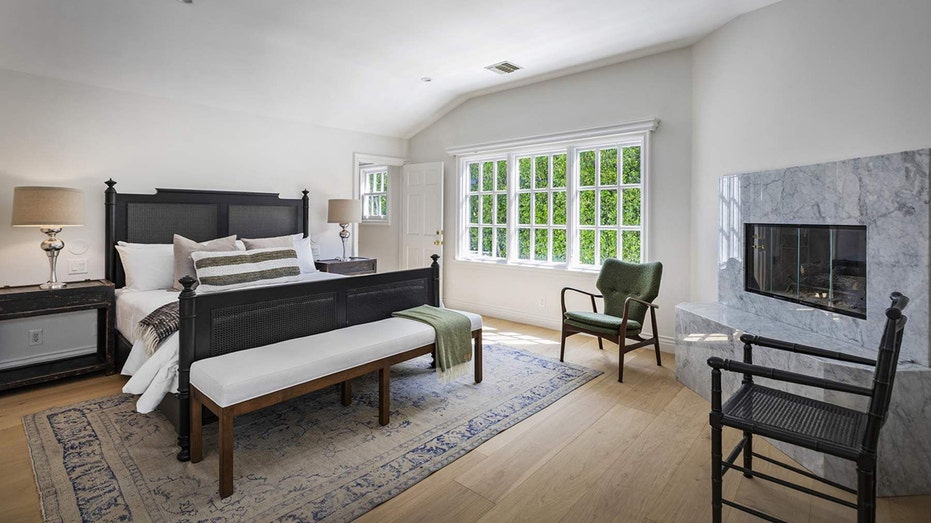 The primary bedroom features a large window and a wood-burning fireplace.