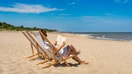 A woman reads a book on a beach. - Fox Business News