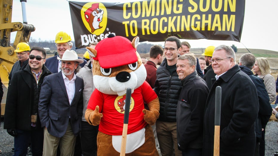 City officials standing next to Buc-ee's beaver mascot for photo at new construction location