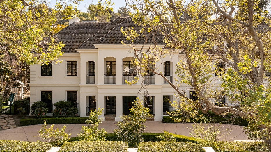 The white exterior of the home is contrasted by the black windows and railings.