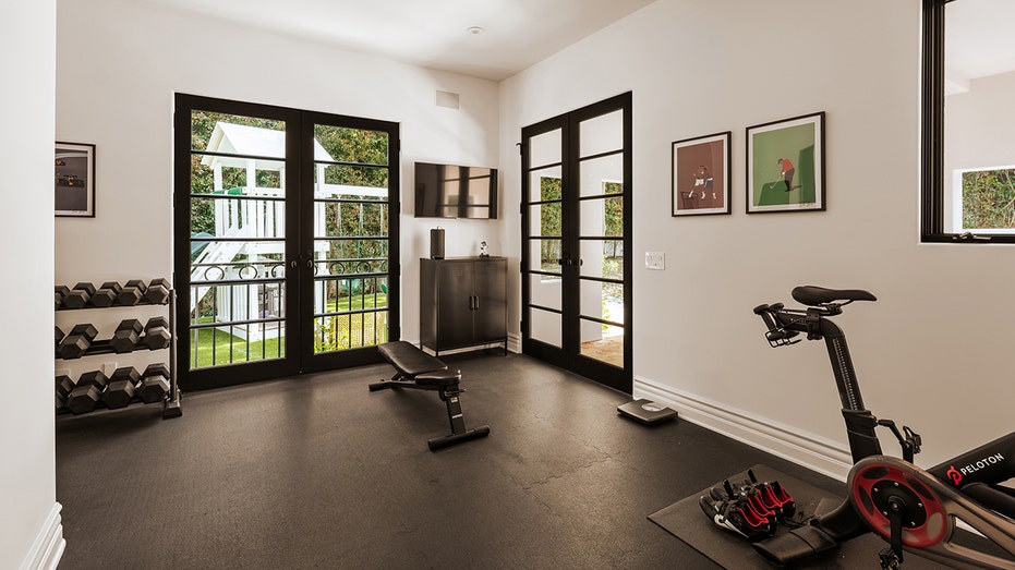 The home gym features a stationary bike and a weight rack.