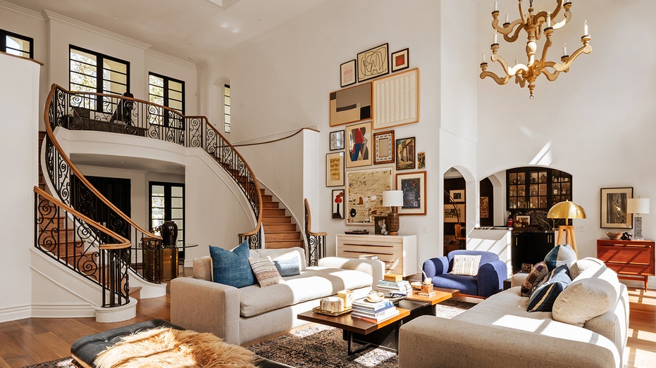 The double-height living room features a gallery wall, a grand staircase and a wood-burning fireplace.