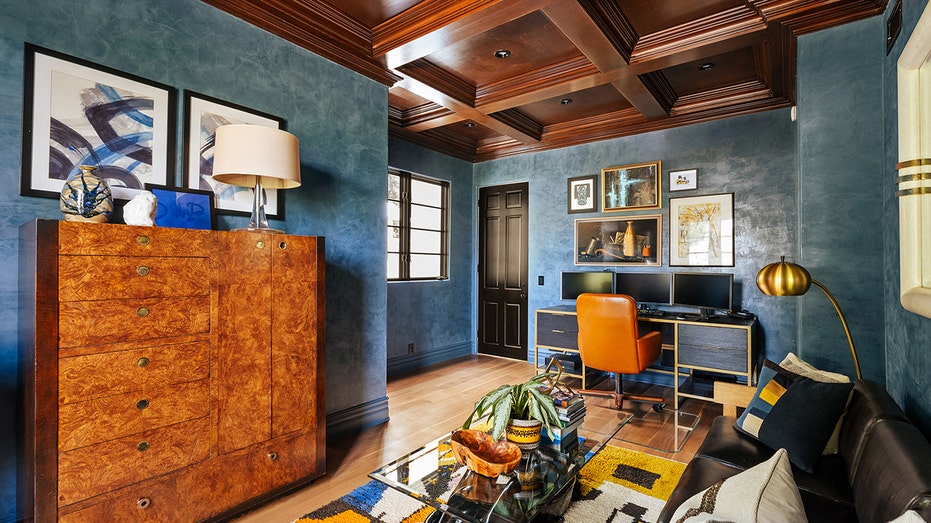 The home office features brown coffered ceilings and blue walls.