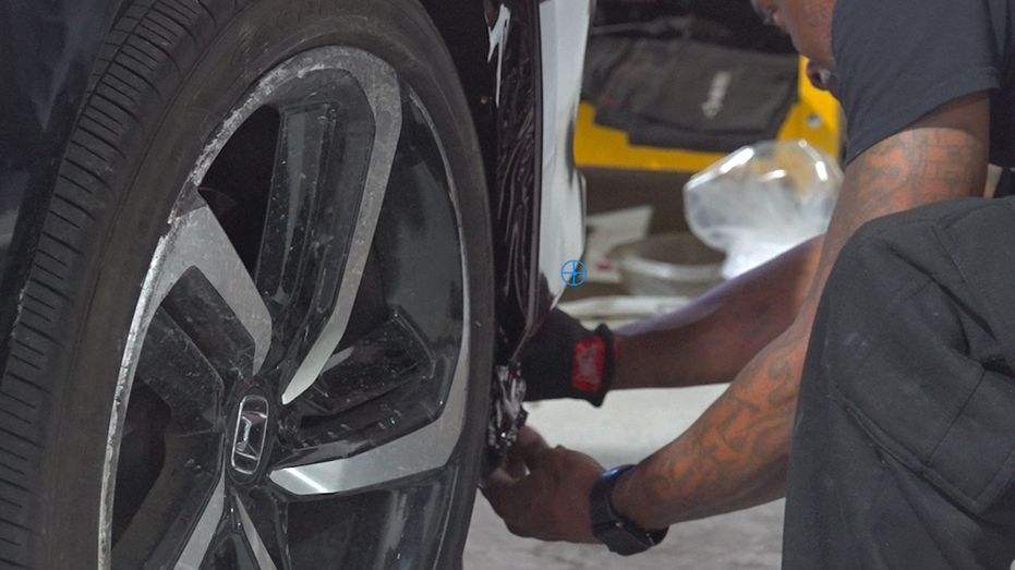 A man is wrapping a car in the shop