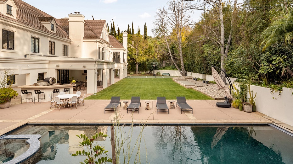The backyard also features an outdoor kitchen with a barbecue and a pizza oven.