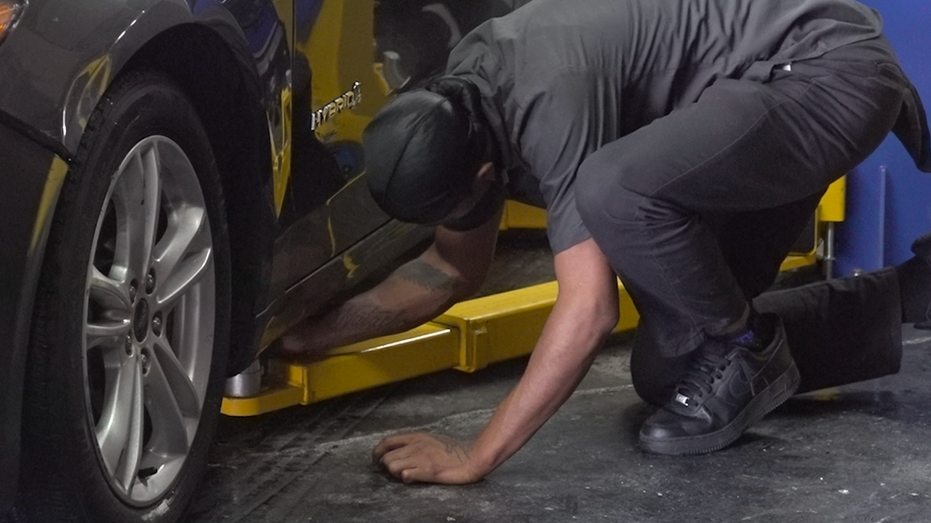 A man is moving a car onto a lift.