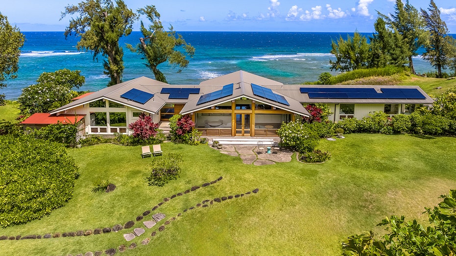 The home is surrounded by lush green grass and trees.