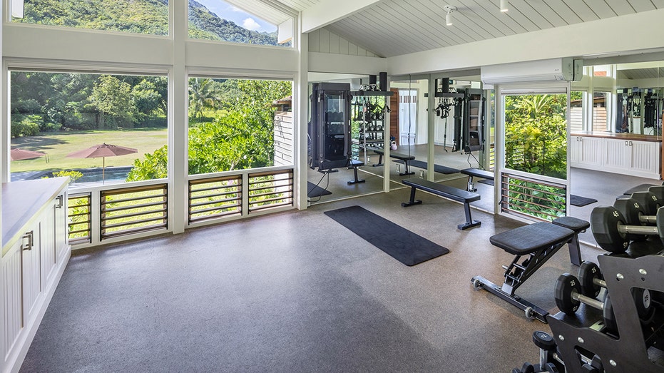 One of the bedrooms has been converted into a gym with a weight rack and bench.