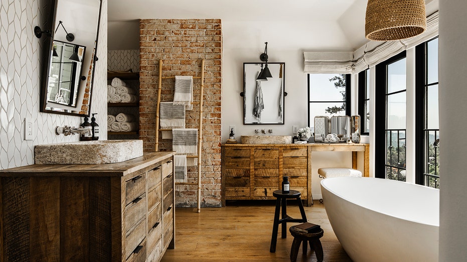 Ensuite bathroom has a tub and emphasis on a brick wall.