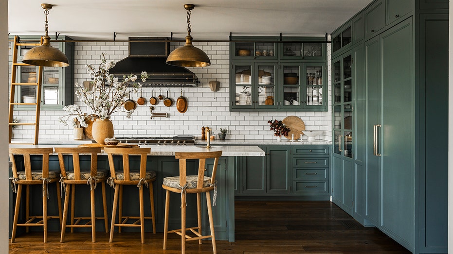 The kitchen has blue green cabinets and a ladder that slips the kitchen from one end of the kitchen.