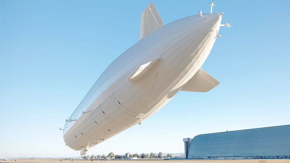 White Pathfinder 1 airship in flight over runway near large hangar at Moffett Federal Airfield