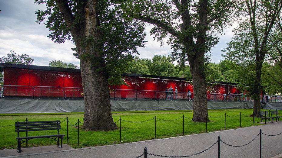 Wide view of red poppy-covered Poppy Wall of Honor installation with visitors walking along the path.