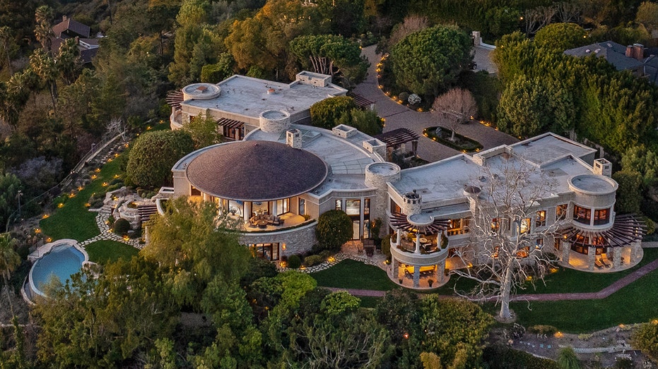 The home features a circular motorcourt, lined with tall trees.