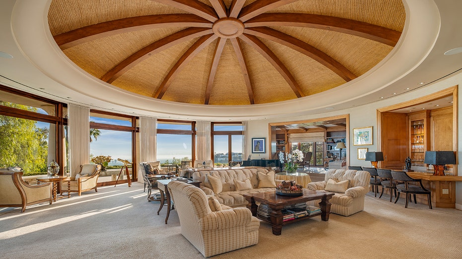 The living room features floor-to-ceiling windows providing picturesque views of the surrounding landscape.