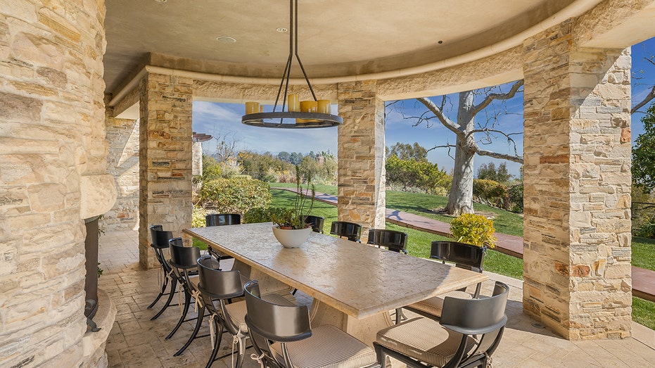 The outdoor dining area features a table large enough for 10 diners and a wood-burning fireplace.