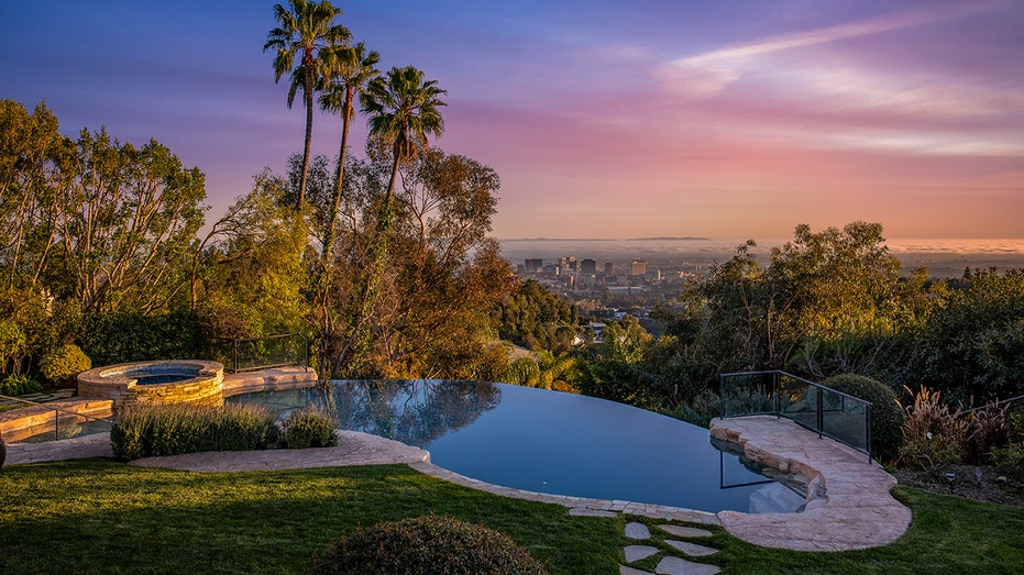 The backyard features lush green grass and a large swimming pool.