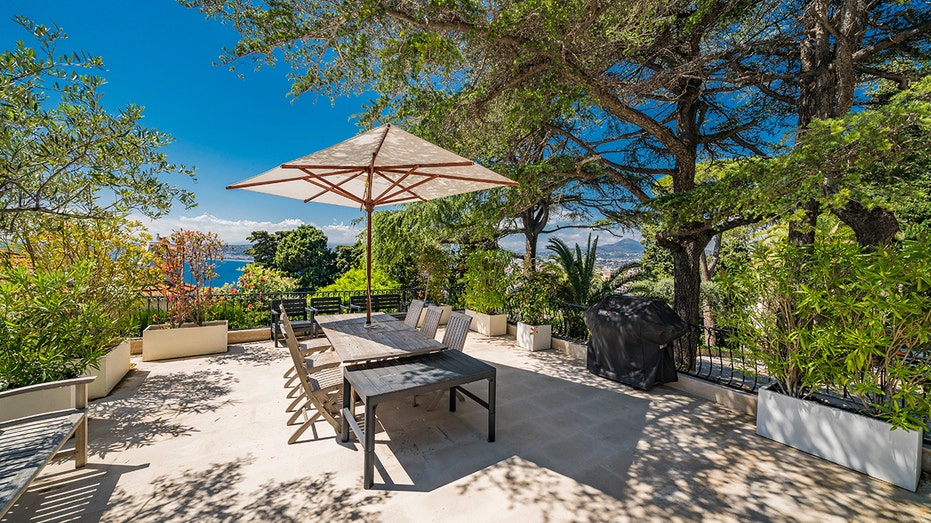 The outdoor dining room features a large table and a barbecue.