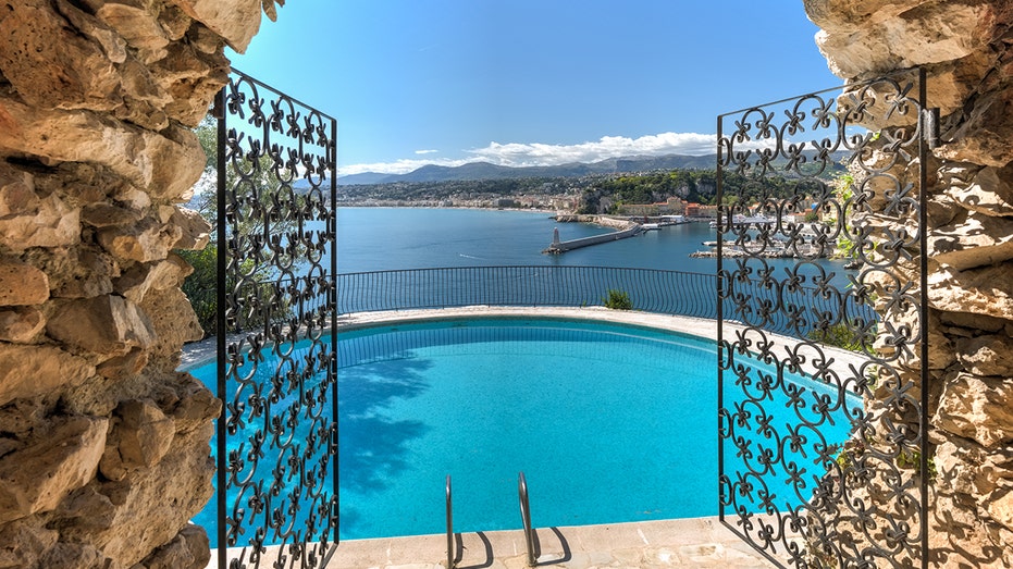 The outdoor infinity pool is accessed through a black iron gate.