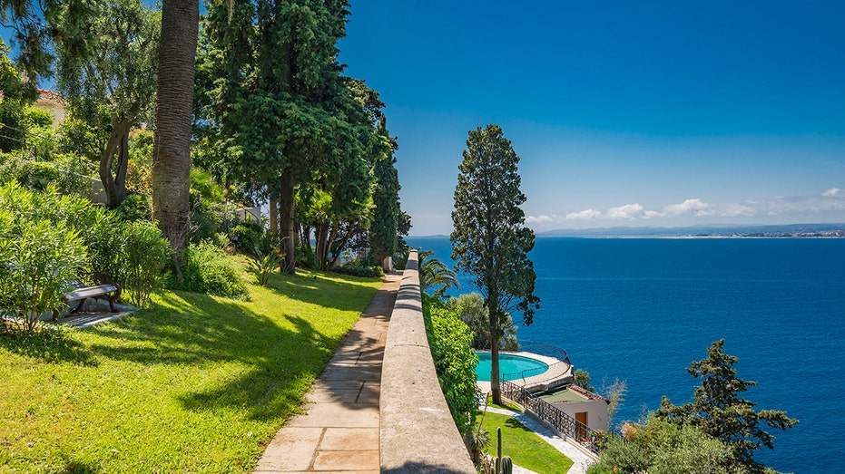 The tiered backyard features lush green areas.