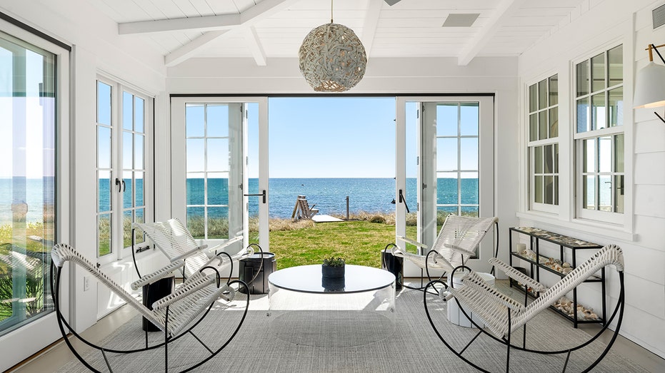 The living room extends to the sun room where windows are lined.