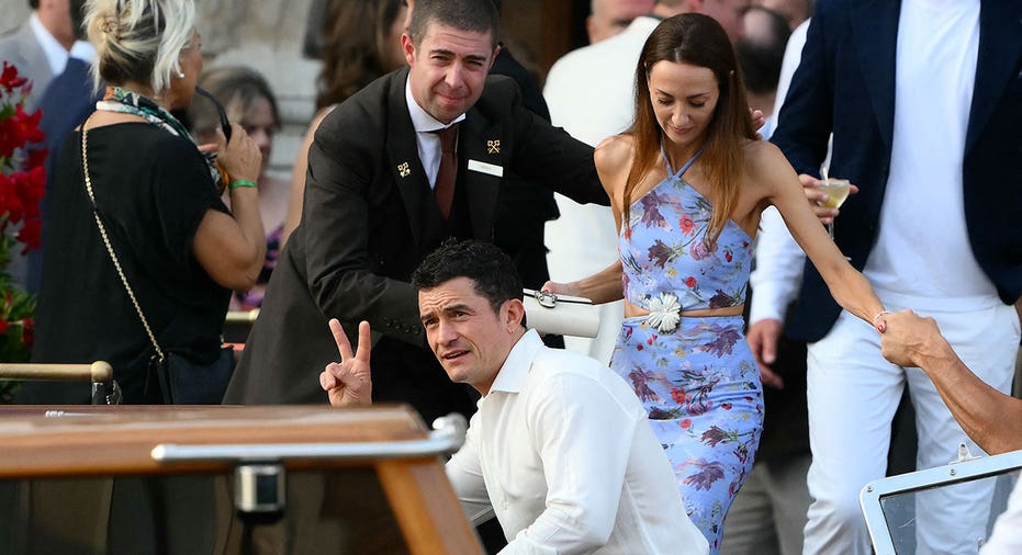 British actor Orlando Bloom and guest get on a taxi boat at the Gritti Palace Hotel ahead of the wedding of Amazon's founder Jeff Bezos with Lauren Sanchez in Venice on June 26, 2026. Celebrities in superyachts sail into Venice this week for the three-day wedding party of Amazon tycoon Jeff Bezos and Lauren Sanchez, despite irate locals who say the UNESCO city is no billionaire's playground. The tech magnate and journalist have reportedly invited about 200 guests to their multi-million dollar nuptials in the Italian city, which are expected to kick off on June 26 and end Saturday with a ceremony at a secret location. (Photo by Marco BERTORELLO / AFP) (Photo by MARCO BERTORELLO/AFP via Getty Images)