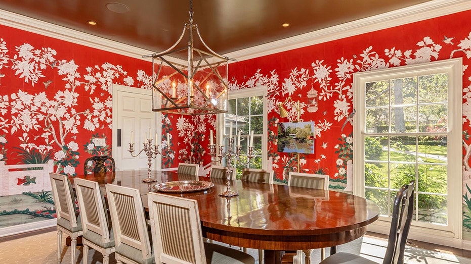 The dining room features bright red wallpaper with white floral designs.
