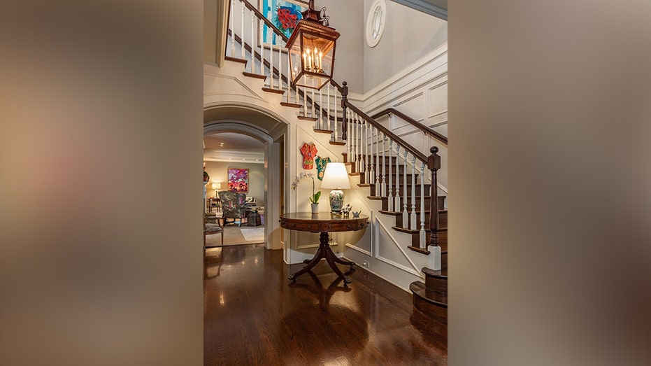 The entryway features a staircase with dark hardwood steps.