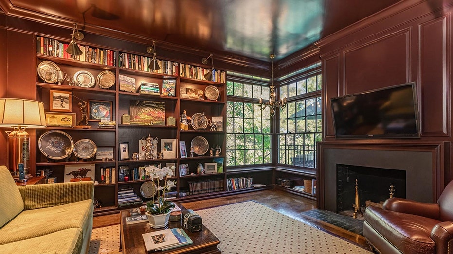 The library features a wood-burning fireplace as well as floor-to-ceiling bookshelves.