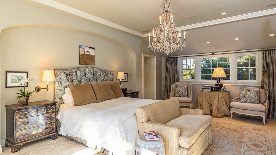 The primary bedroom features a chandelier in the center of the room as well as windows.