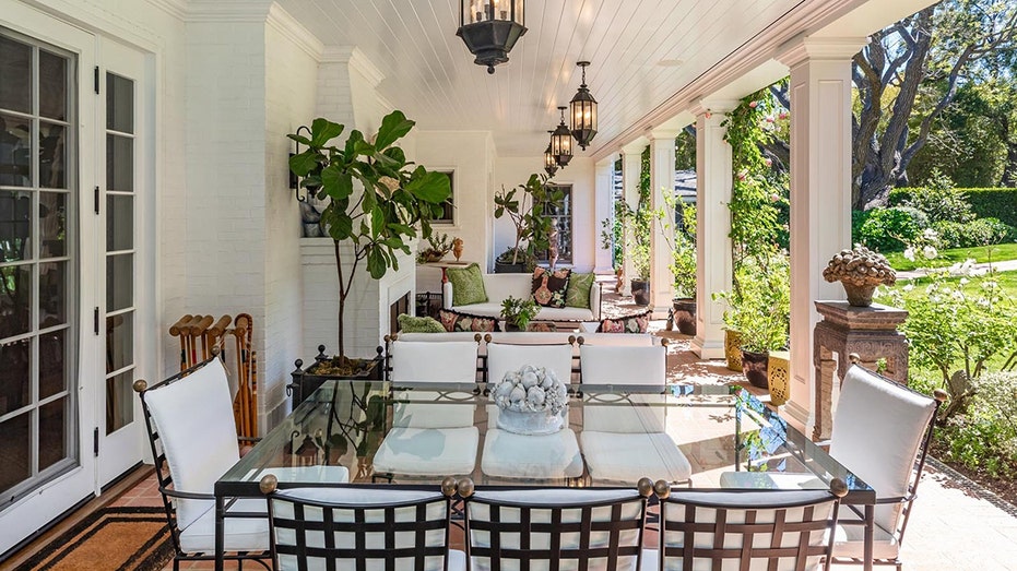 The covered front porch features an outdoor seating and dining area with an outdoor fireplace.