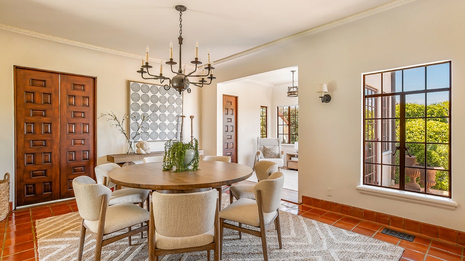 The dining room features a circular table and windows looking into the backyard.