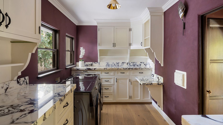 The laundry room features plenty of counter and storage space as well as walls painted purple.
