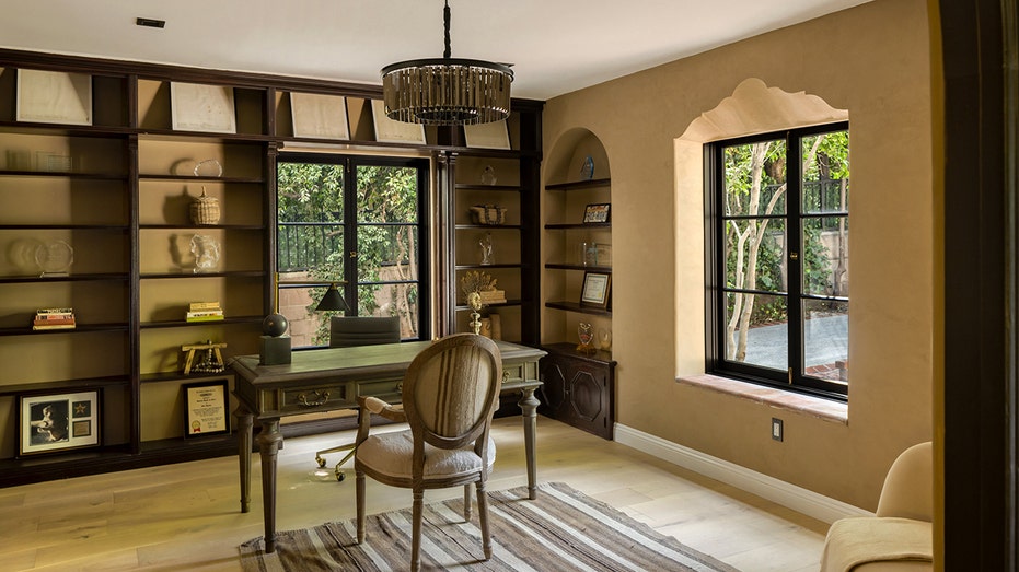 The office includes built-in shelves and multiple windows.