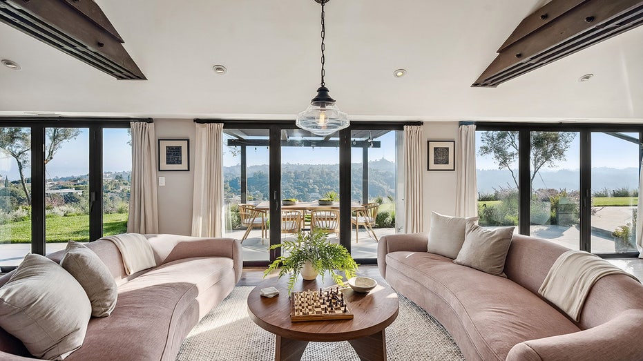 The family room features floor-to-ceiling glass doors which open up onto an outdoor eating area.