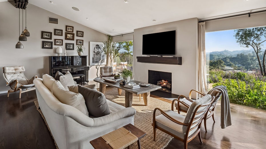 The living room features floor-to-ceiling windows, a wood-burning fireplace and dark hardwood floors.