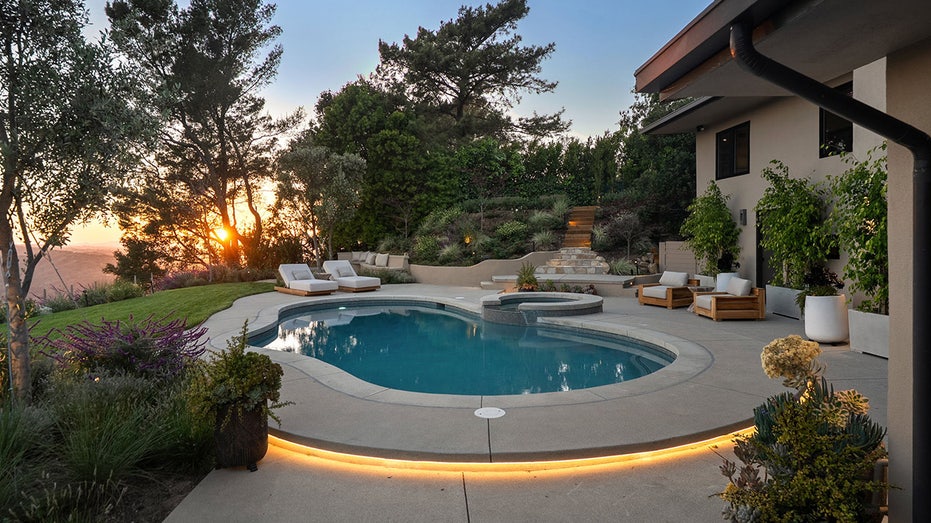 The backyard also features a swimming pool with lounge chairs all around it.