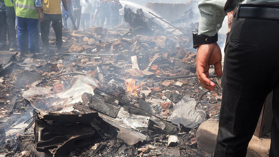 People stand by debris of Air India flight