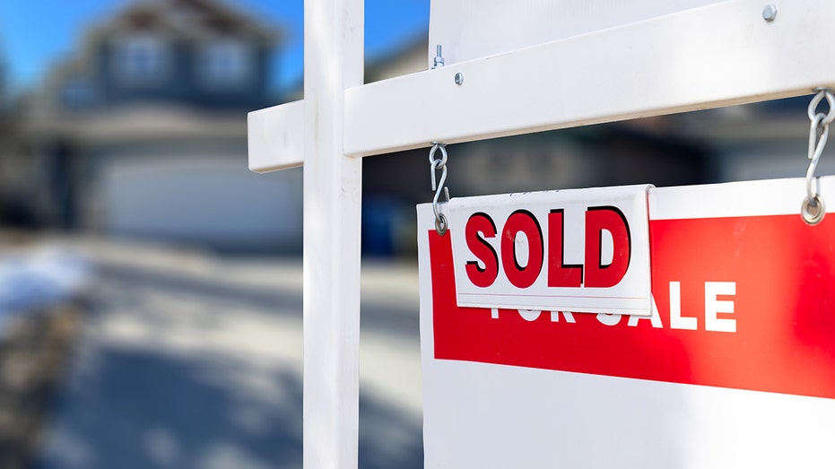 A home for sale sign has 'sold' sticker on top